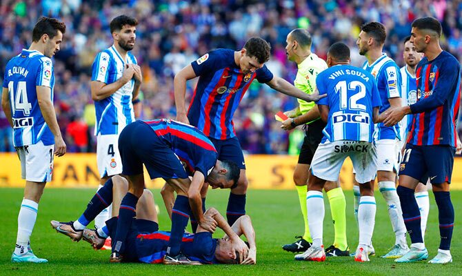 Jugadores de Barcelona y Espanyol rodean al árbitro en un derbi catalán de 2022